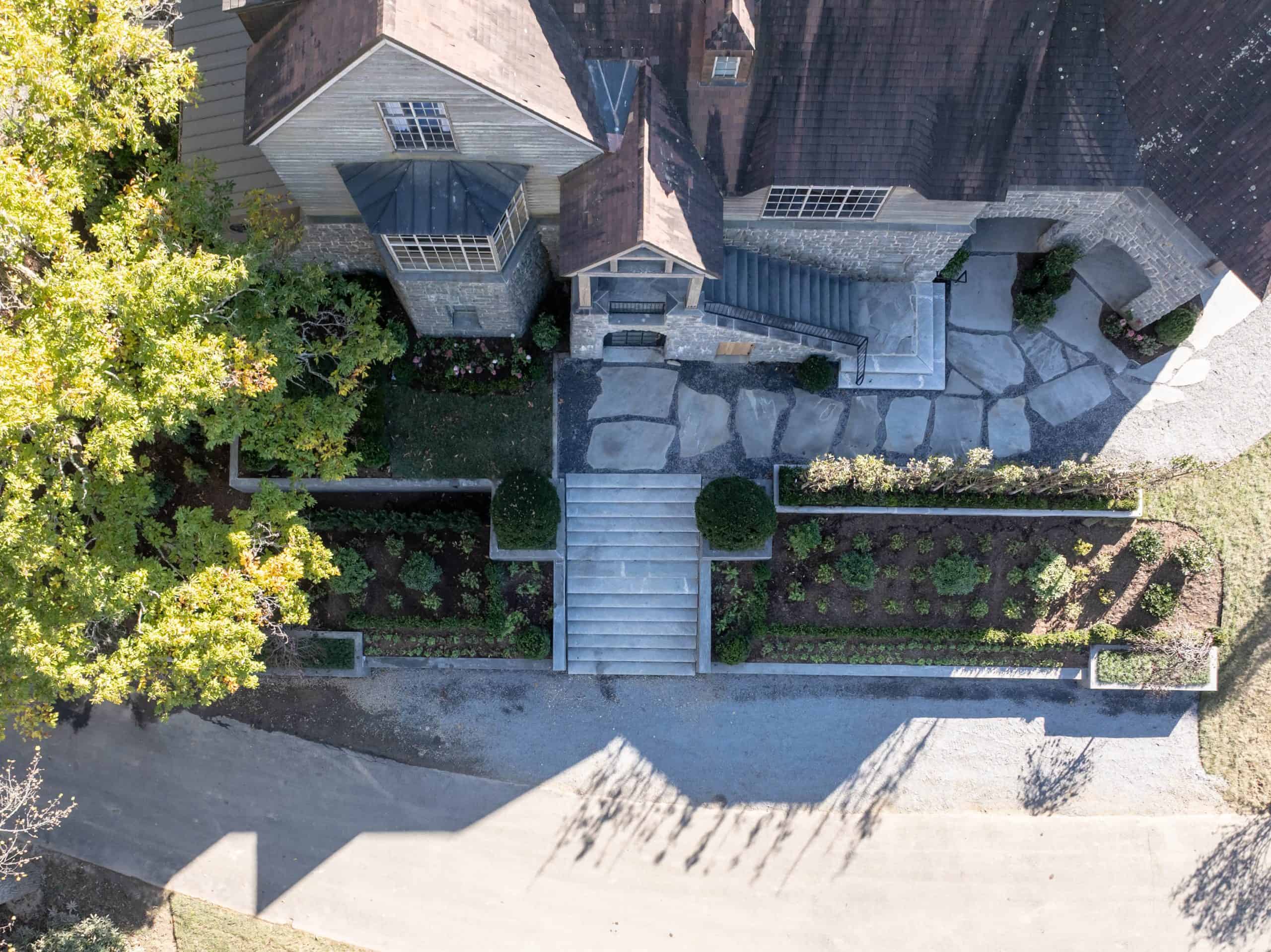 Aerial overhead view of luxury estate garden design with flagstone terrace, formal planting beds, and stone manor at Ahma at Cold Mountain, Canton NC