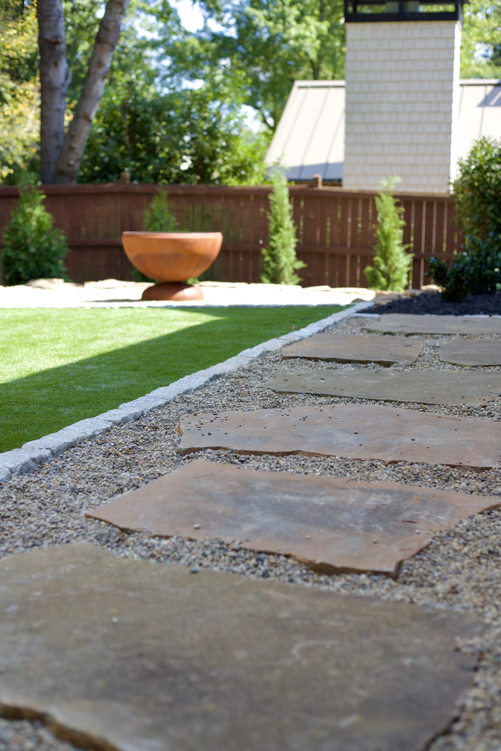 Natural stone boulder wall with artificial turf and corten steel fire pit at the Woods Residence, Chastain Park, Atlanta by Garden Atlantic