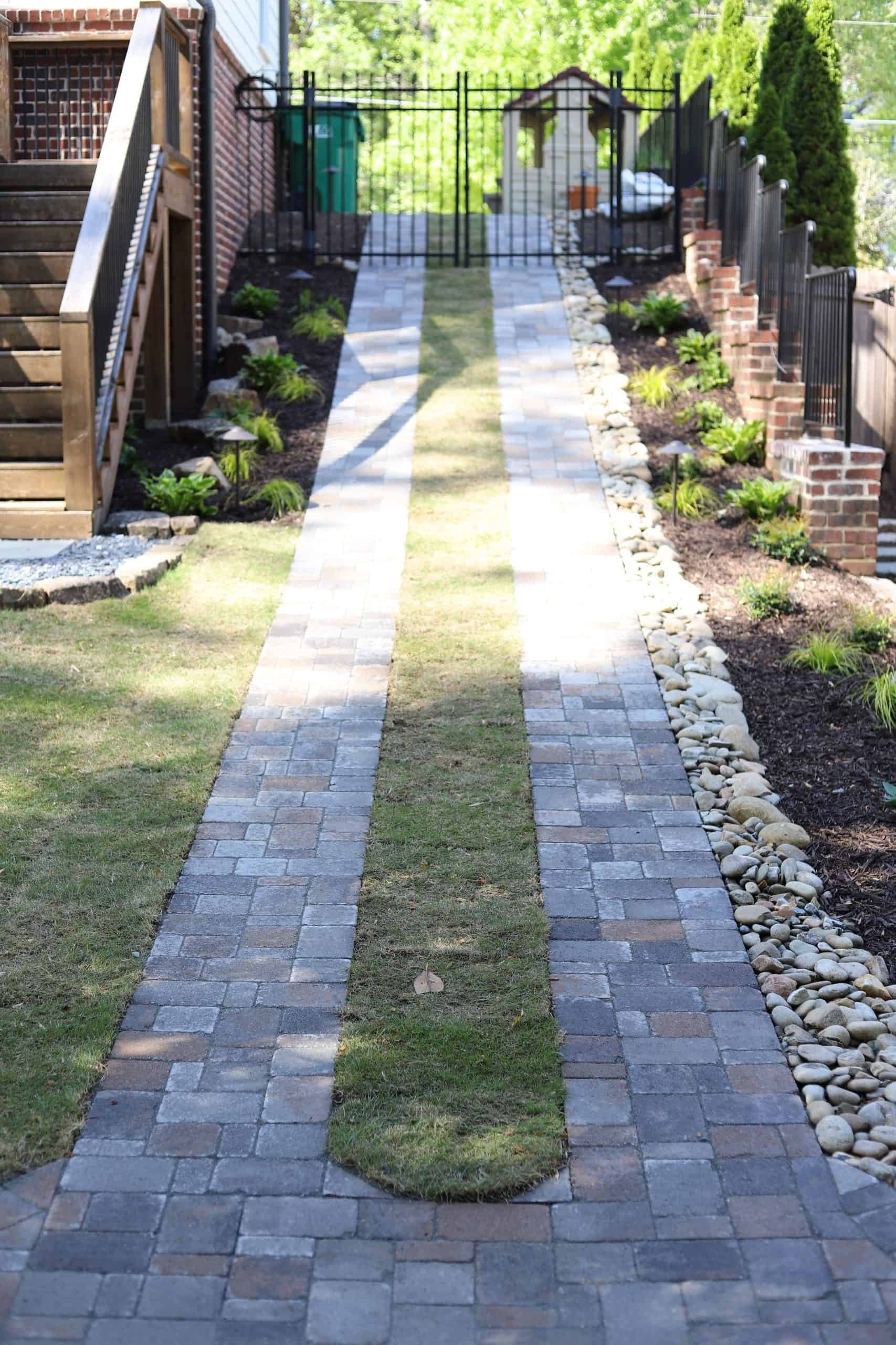 Side yard paver walkway with landscape lighting and river rock border leading to backyard at the Healy Project, Chastain Park, Atlanta