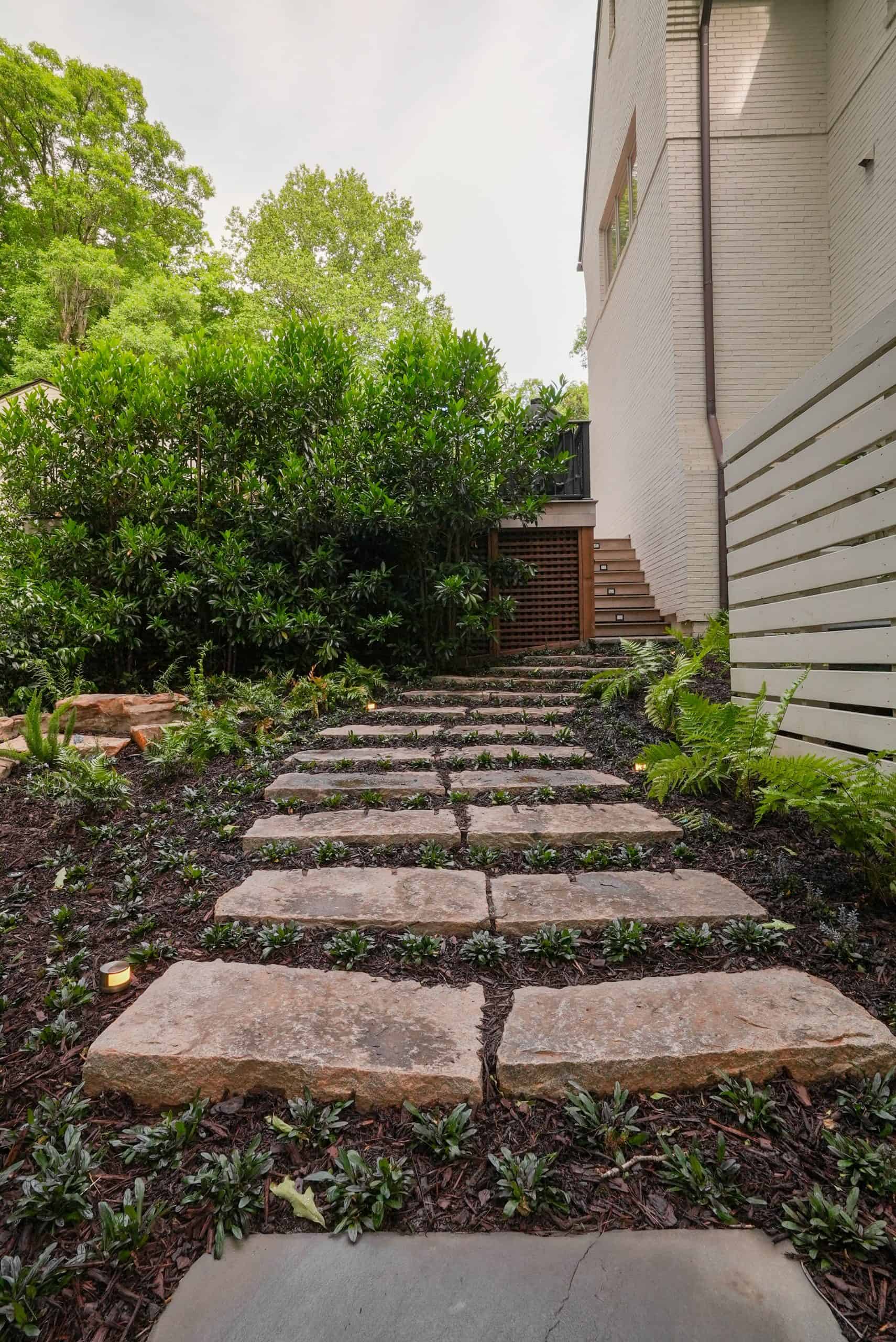 Bluestone stepping-stone path set in groundcover with ferns and low landscape lighting in a Buckhead estate garden by Garden Atlantic.