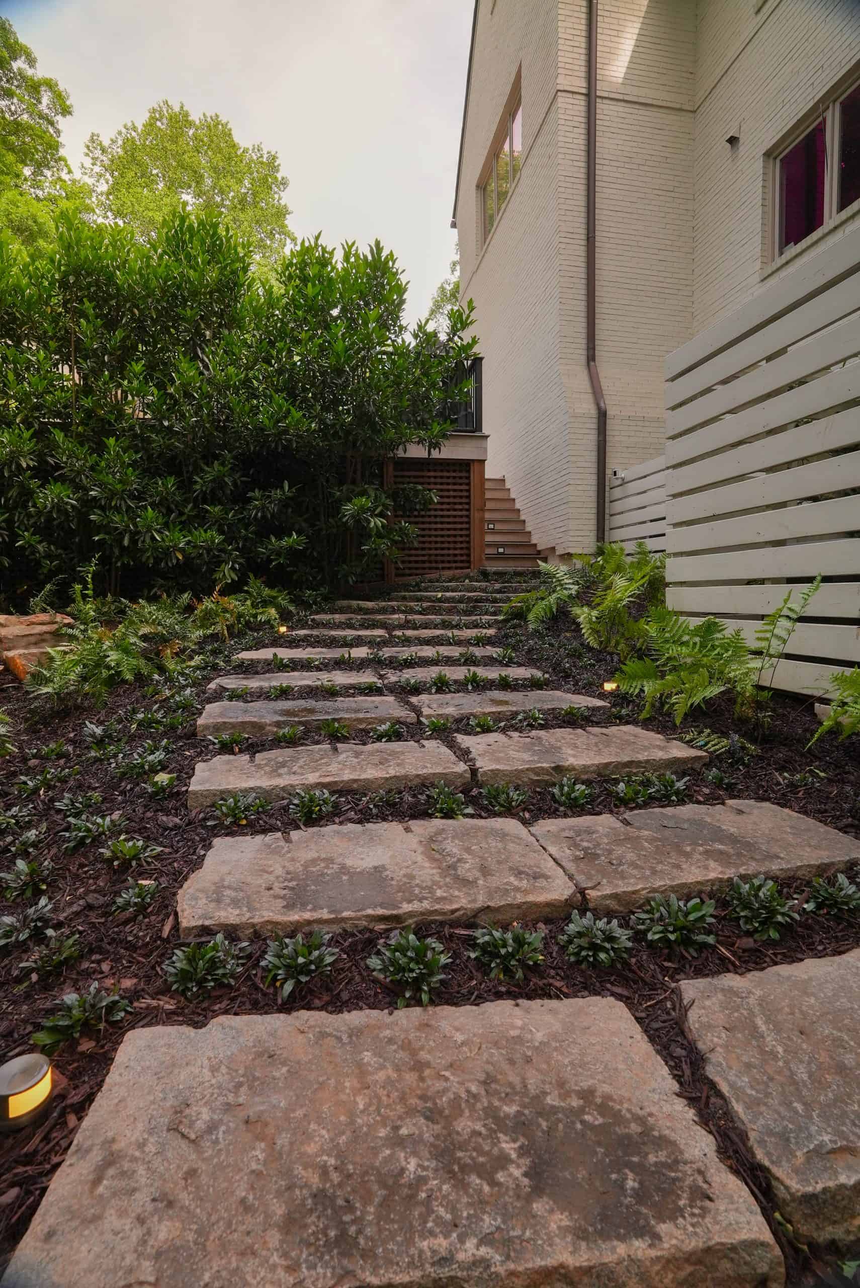 Stone stepping-path with glowing cast brass landscape lighting and ferns in a Buckhead estate garden.